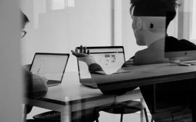 Two individuals working together at their laptops