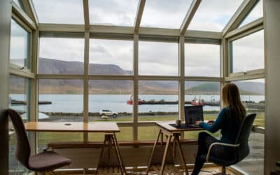 Woman works remotely by a window with a waterfront view