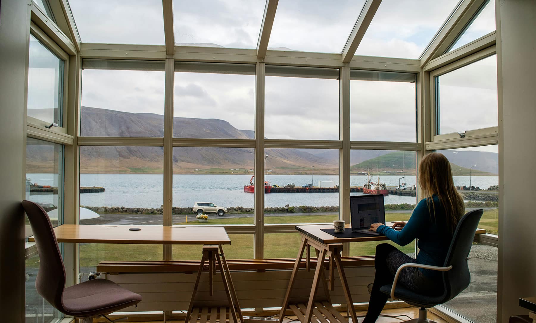 Woman works remotely by a window with a waterfront view