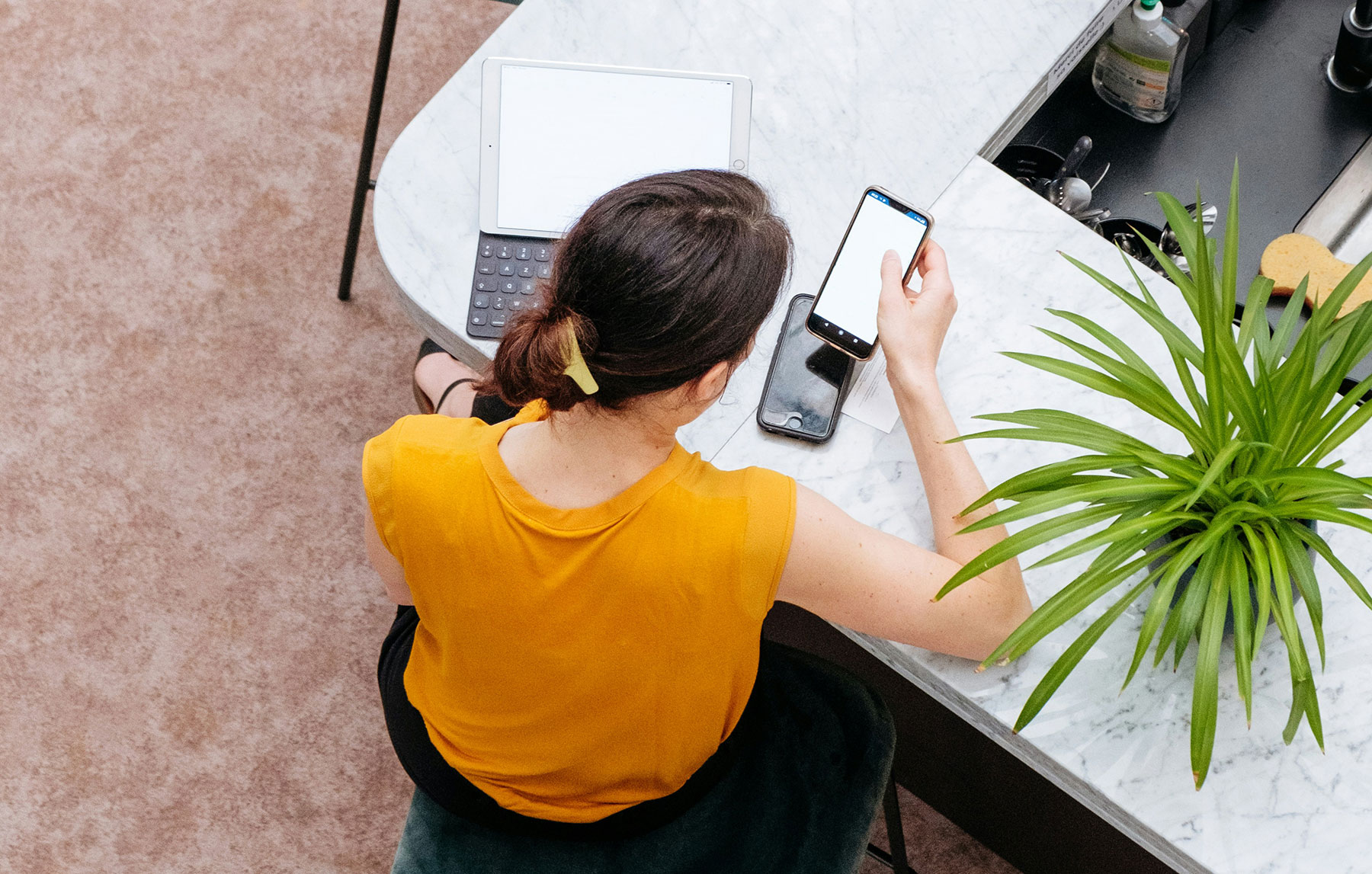 Woman looks at her phone and laptop screen