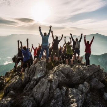 Team of hikers celebrate at the summit of a mountain.